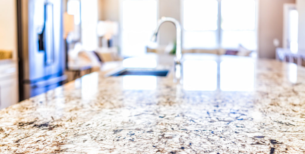 New modern faucet and kitchen room sink closeup with island and granite countertops in model house, home, apartment